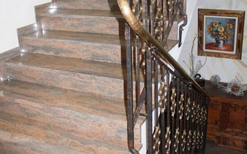 Eine Treppe aus Marmor mit einem Metallgeländer und einem Gemälde an der Wand.