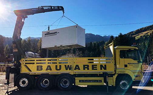 Einer unserer Lkw hebt einen Container auf eine Plattform.